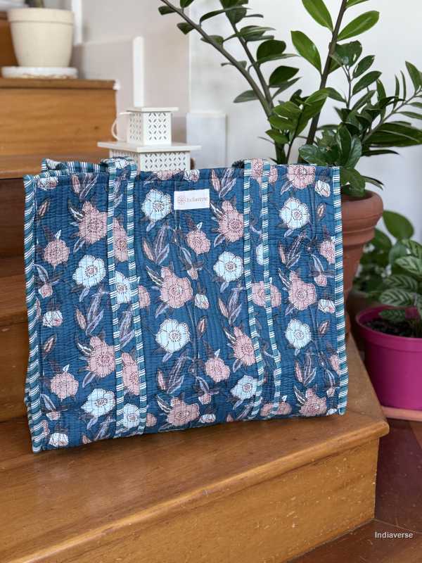 beautiful hand block printed quilted cotton tote bag with pink and off white floral design perfect tot carry all your essentials sitting on wooden staircase with plants in background