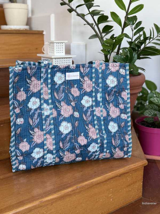 beautiful hand block printed quilted cotton tote bag with pink and off white floral design perfect tot carry all your essentials sitting on wooden staircase with plants in background