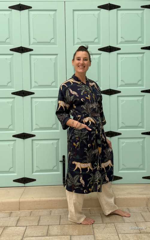 Woman wearing a dark blue waffle cotton bathrobe with jungle animals and tropical motifs, smiling and posing casually