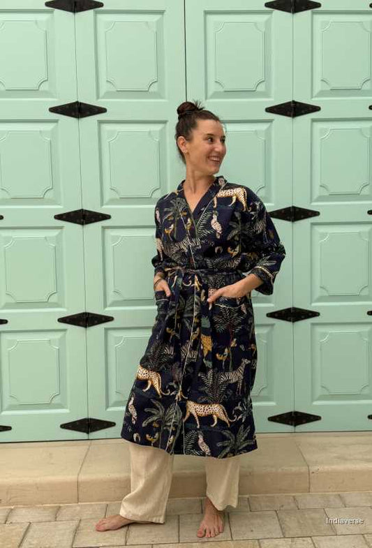 Woman wearing a dark blue waffle cotton bathrobe with jungle animals and tropical motifs, smiling and posing casually