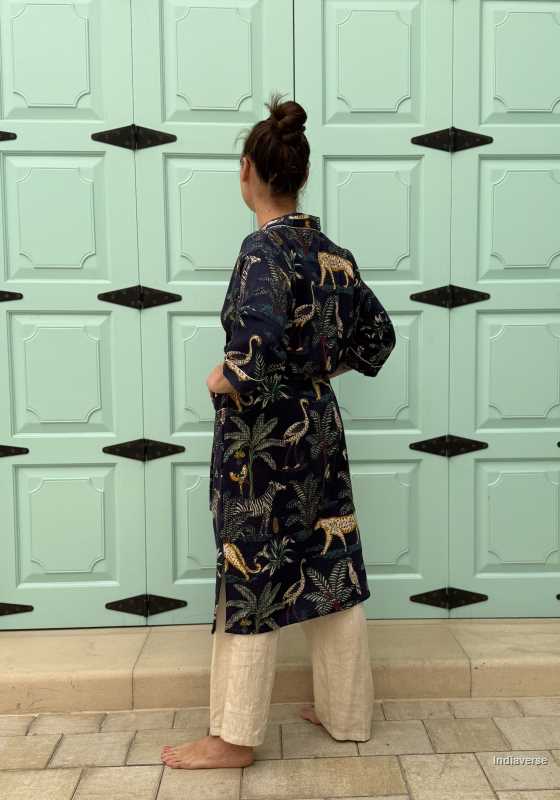 Woman wearing a dark blue waffle cotton bathrobe with jungle animals and tropical motifs, smiling and posing casually