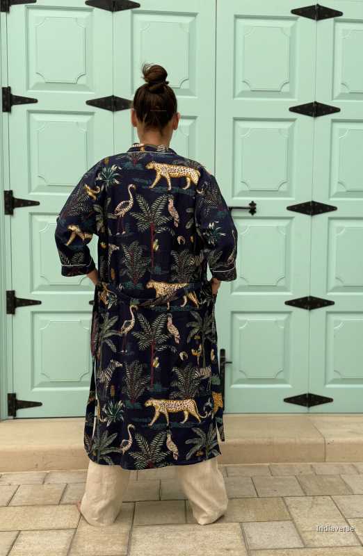 Woman wearing a dark blue waffle cotton bathrobe with jungle animals and tropical motifs, smiling and posing casually