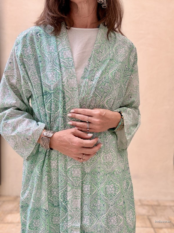 Woman wearing a green patterned kimono-style garment against a beige background