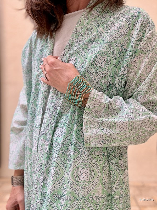 Person wearing a green patterned kimono-style garment against a beige background