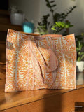 Patterned fabric tote bag on a wooden surface with plants in the background