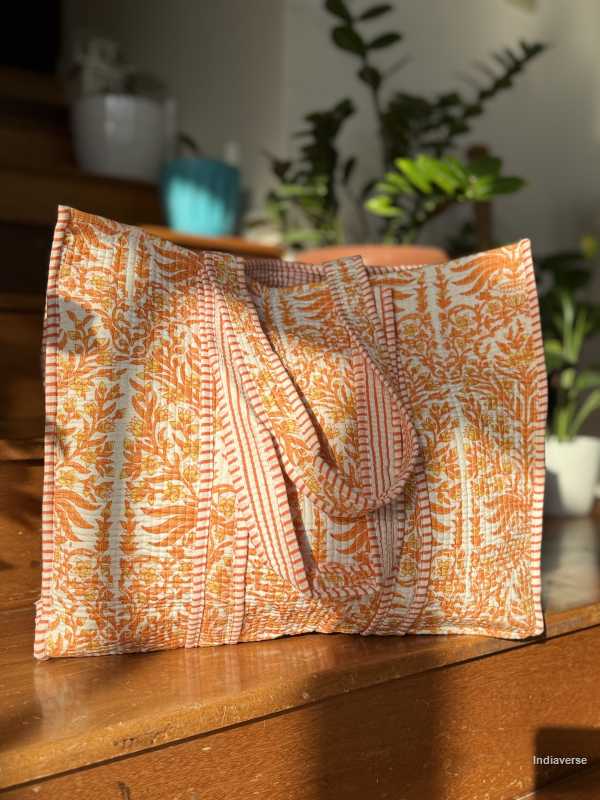 Patterned fabric tote bag on a wooden surface with plants in the background