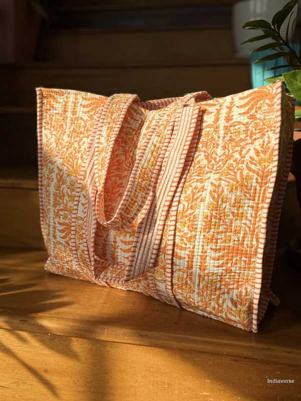 Floral patterned orange white tote bag on a wooden surface with a blurred background
