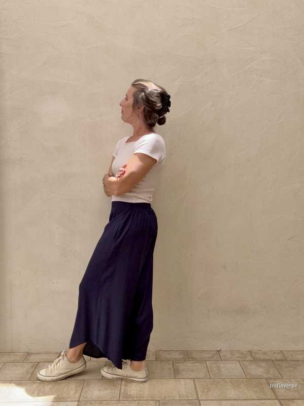Woman leaning against a beige wall with dark blue palazzo pants