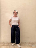woman wearing royal blue palazzo pants is standing against a beige wall