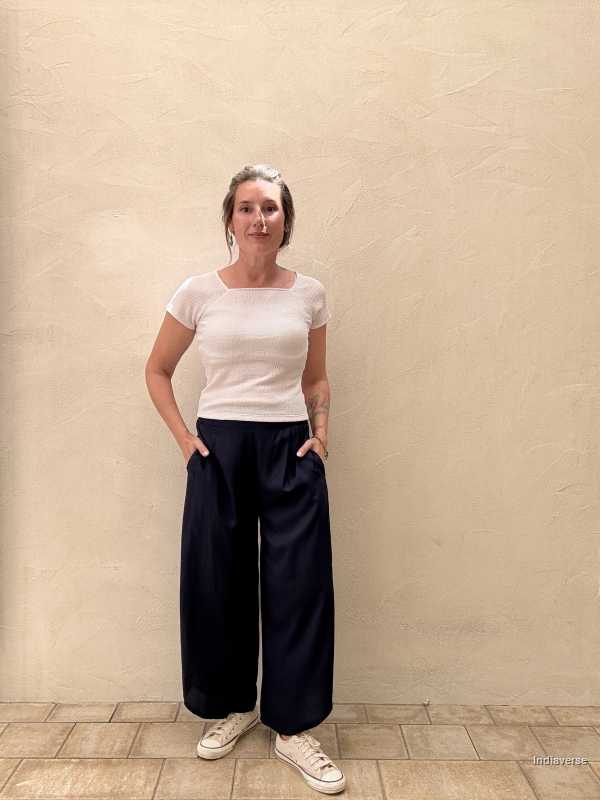 woman wearing royal blue palazzo pants is standing against a beige wall