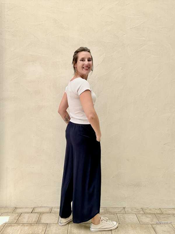 a woman is smiling and turning back and she is wearing dark blue palazzo pants and a light pink top