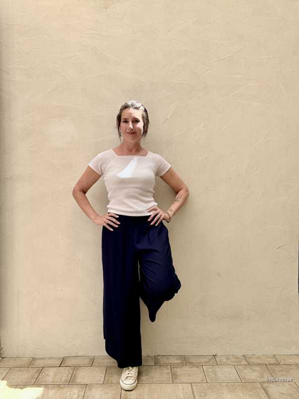 Woman leaning against a beige wall wearing a pair of royal blue pants