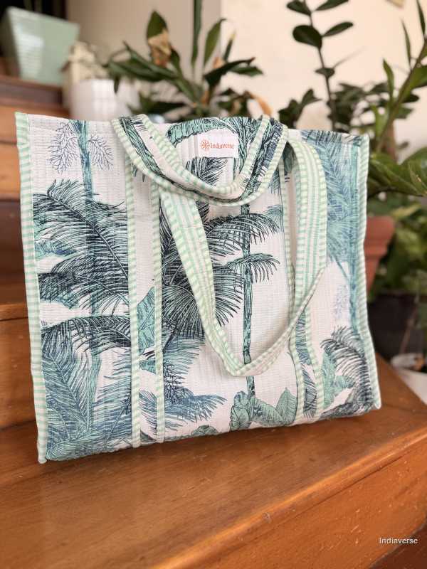 Tropical patterned tote bag on a wooden surface with plants in the background