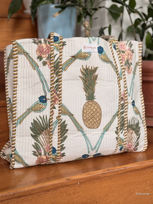 tote bag with pineapple and bird motif standing on a wooden floor