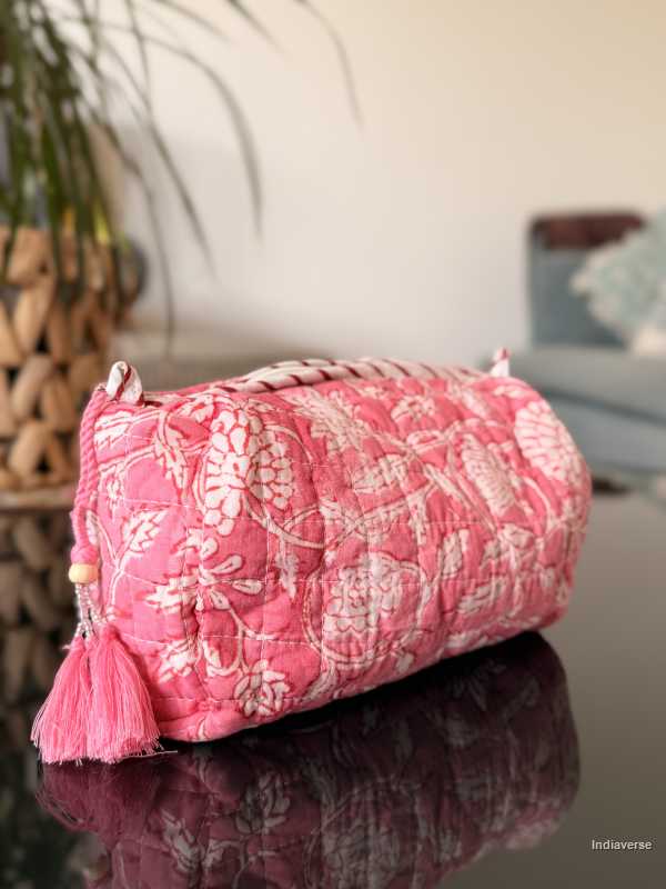 Pink floral-patterned cylindrical bag with tassels on a reflective surface | Pink Delight