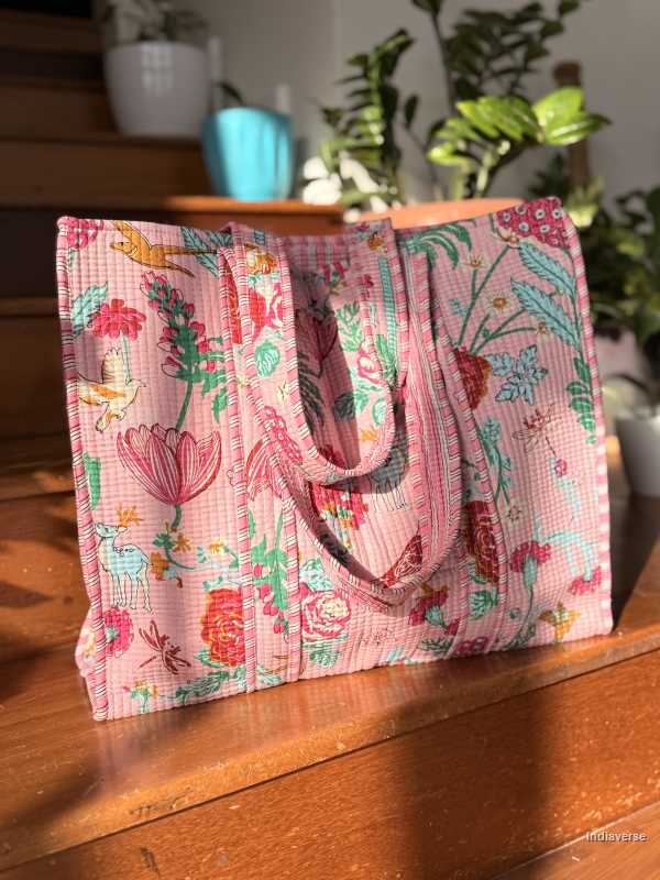 Floral-patterned tote bag on a wooden surface with plants in the background