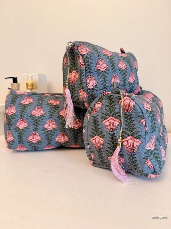 Three fabric cosmetic pouches in a matching blue floral print with pink lotus flowers and green leaves, arranged on a light surface against a plain beige background | Pink Lotus