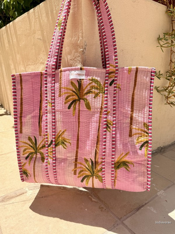 Pink tote bag with palm tree design on a light background