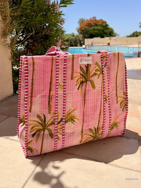 Pink tote bag with palm tree design on a patio