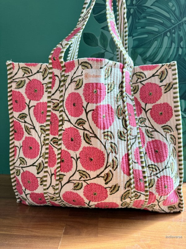 Floral embroidered bag with pink flowers on a wooden surface and green leafy background