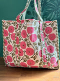 Floral embroidered bag with pink flowers on a wooden surface and green leafy background