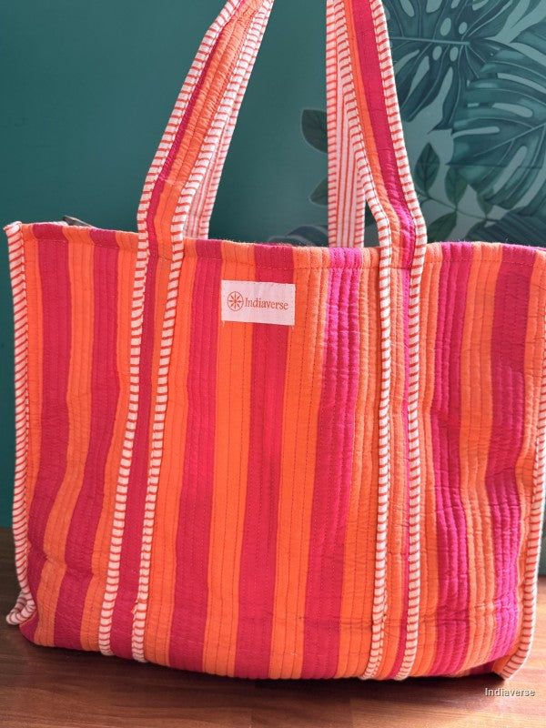 quilted tote bag with orange and pink stripes in front of a green wall