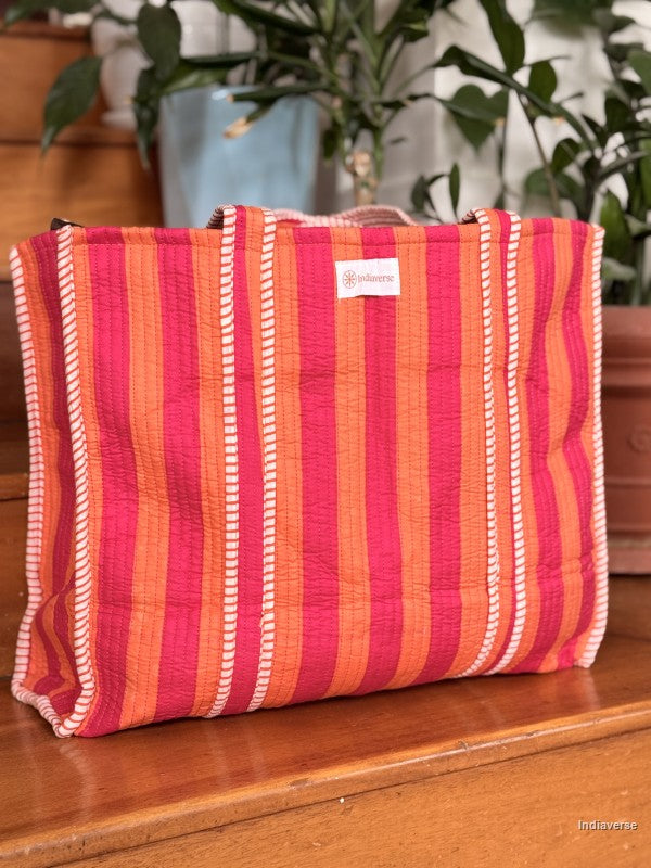 quilted tote bag with pink and orange stripes sitting on a wooden surface