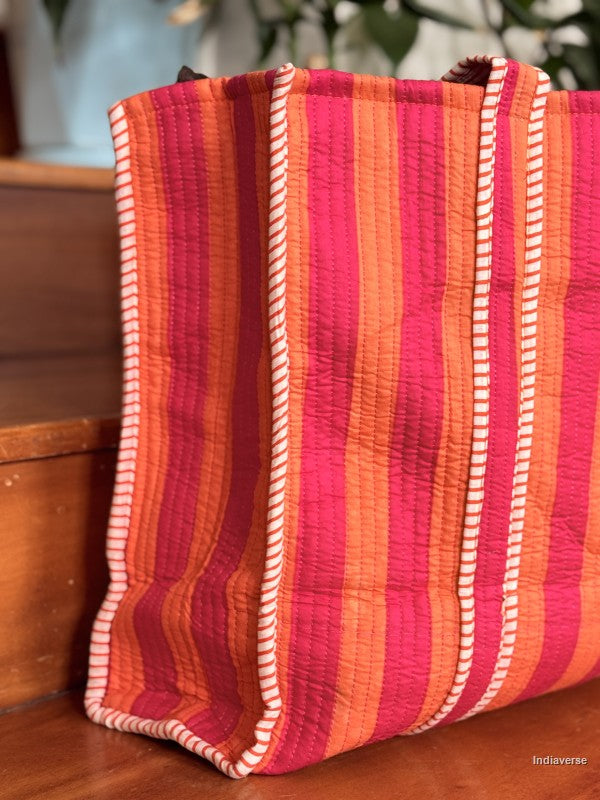 side view of the pink and orange quilted tote bag sitting on a wooden surface