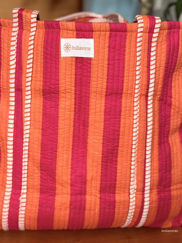 close up of the front of the quilted tote bag with pink and orange stripes and showing the label Indiaverse