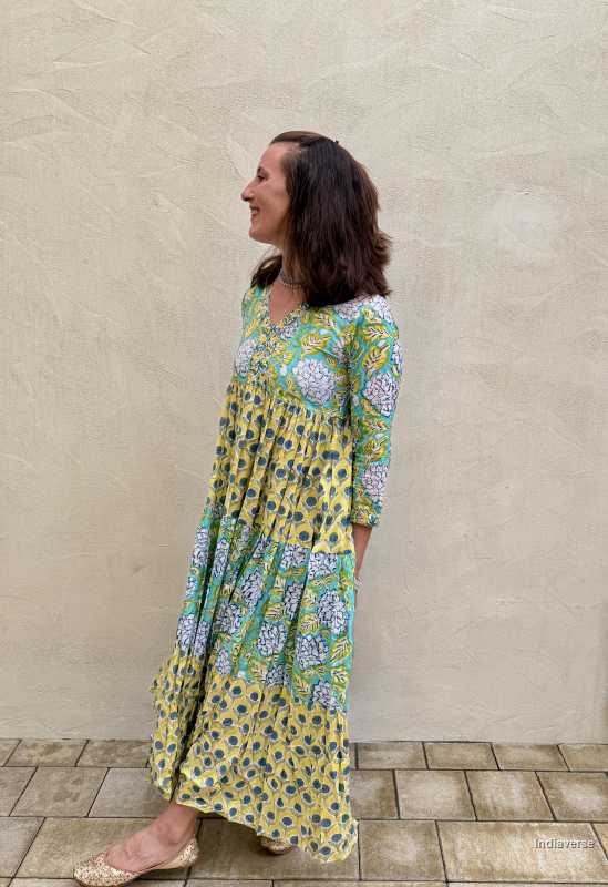 Woman wearing a floral dress standing against a beige wall.