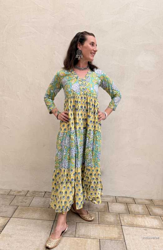 Woman wearing a colorful dress with a patterned design against a beige wall.