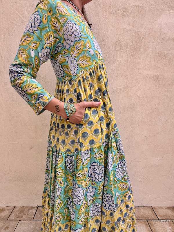 Woman wearing a colorful floral dress against a beige wall.