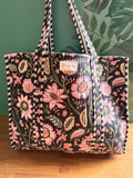 Floral-patterned bag on a wooden surface with a green leafy background