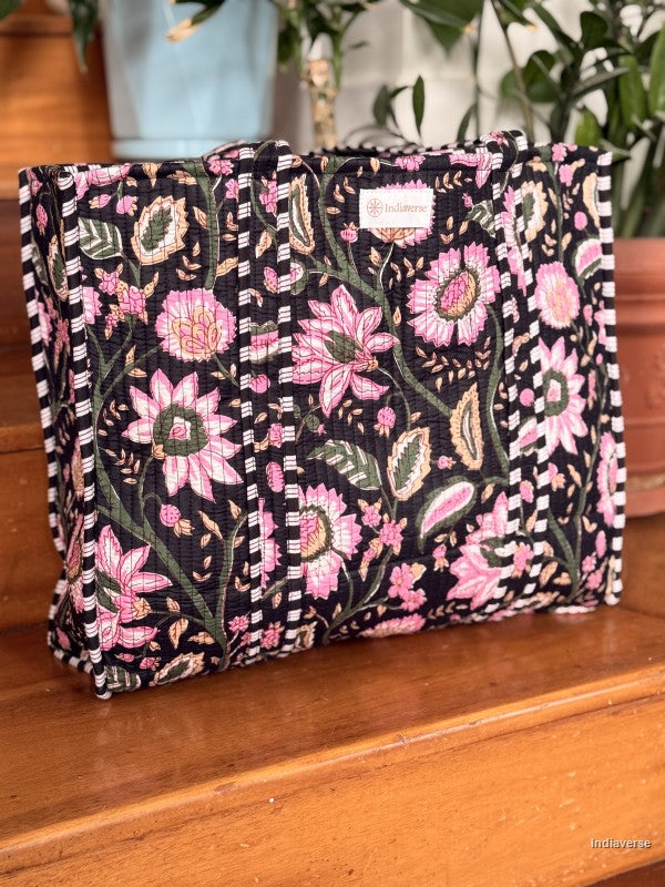 Floral patterned bag on a wooden surface with plants in the background