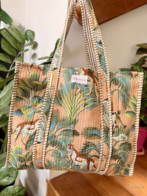 Tropical patterned tote bag with woven handles on a wooden surface.