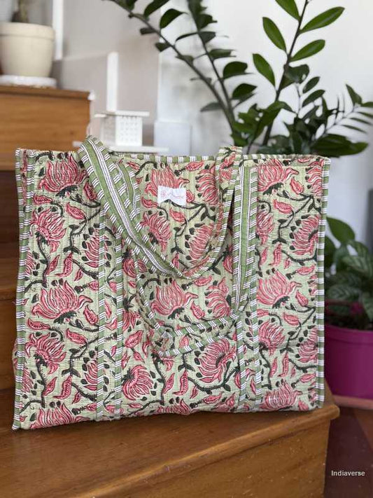 Quilted cotton tote bag in melon hue with red floral design sitting on wooden staircase with plants in background  | Spring Queen