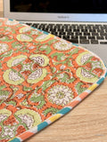 Floral-patterned laptop sleeve on a desk with a laptop in the background