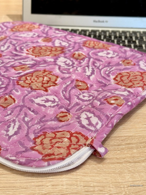Pink floral laptop sleeve on a wooden surface with a laptop partially visible.