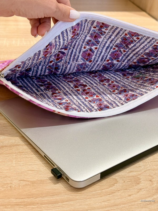 Person holding a patterned fabric over an open laptop on a wooden surface