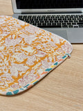 Floral laptop sleeve on a wooden desk with a laptop in the background