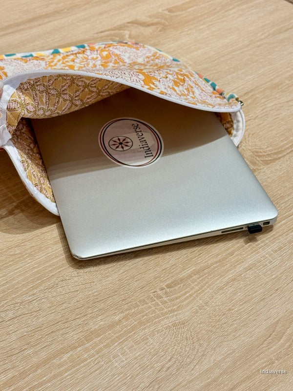 Silver laptop with a brand logo inside a floral-patterned fabric cover on a wooden surface