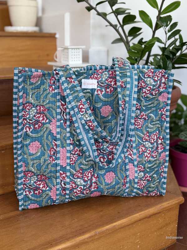beautiful hand block printed quilted cotton tote bag with water inspired floral design perfect tot carry all your essentials sitting on wooden staircase with plants in the background