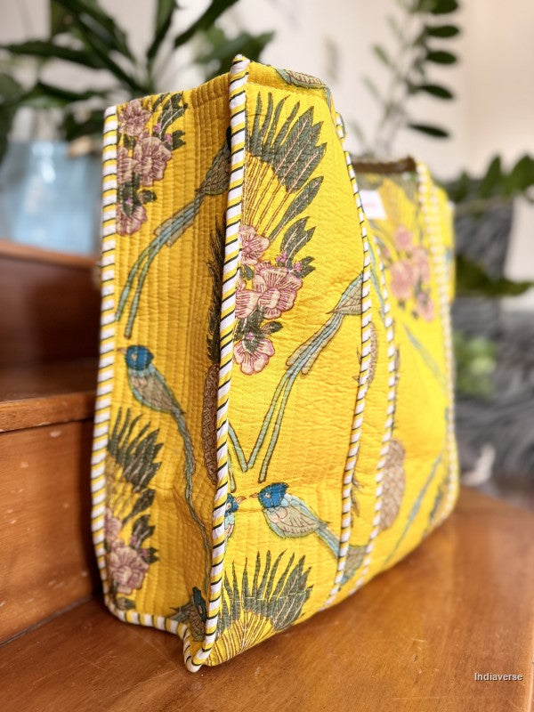 Yellow floral and bird patterned clutch bag on a wooden surface with a blurred background