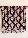 black cotton scarf with red tiger print hanging from a wooden beam