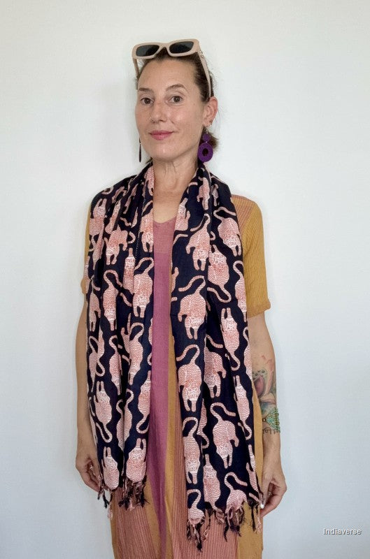 woman wearing a black scarf with red tiger design standing against a white wall