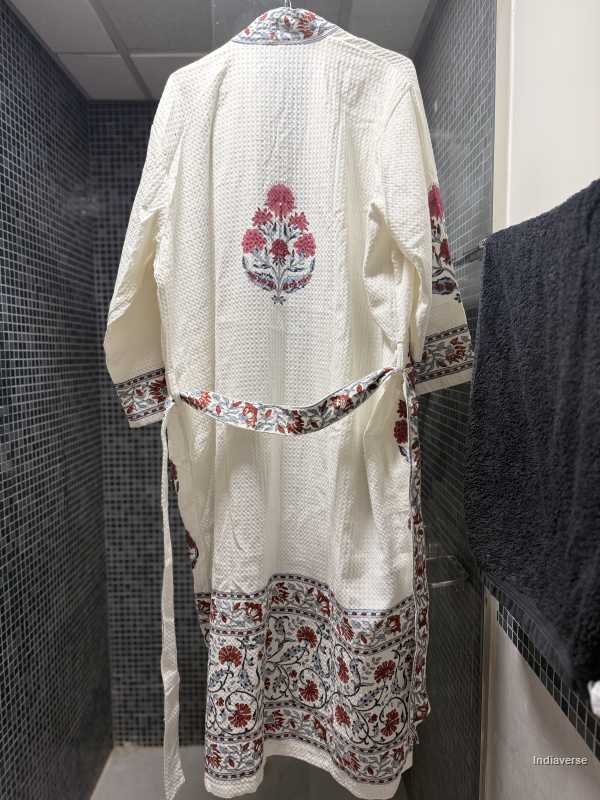 White traditional outfit with floral patterns hanging against a tiled wall.