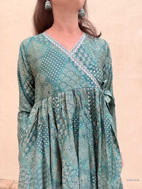 Teal patterned dress worn by a person on a beige background