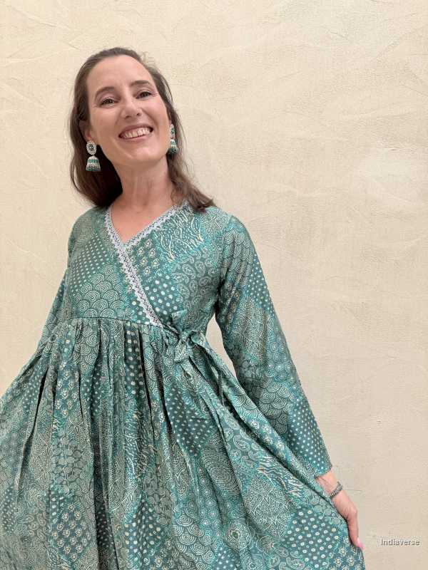 Woman wearing a teal patterned dress against a beige background