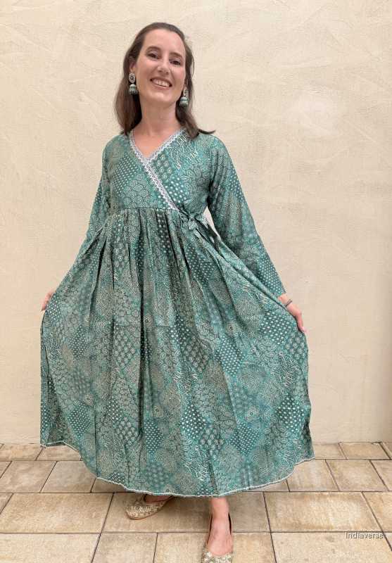 Woman wearing a green patterned dress against a beige wall.