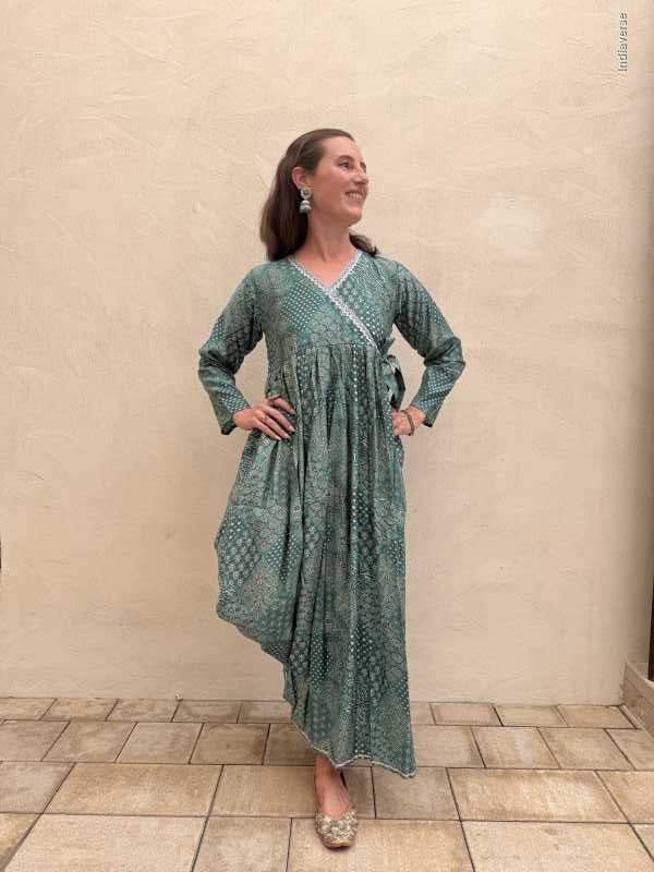 Woman wearing a long green dress standing on a tiled floor.